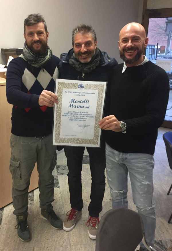Roberto e Daniele Martelli della ditta Martelli Marmi srl e al centro Stefano Sabattini di Cna Bologna, con la pergamena "Buon Anniversario" per i 50 anni di attività dell'azienda